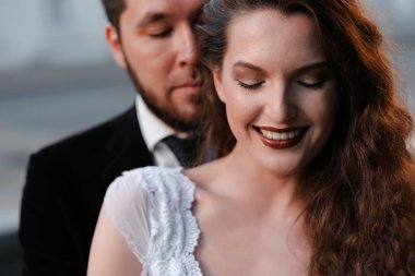 Bulanık şehir arka bahçesinde poz veren güzel yeni evli çift.