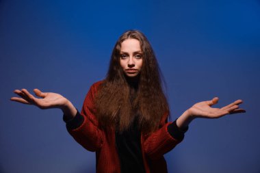 Mavi arka planda, boşanmış ellerle poz veren tatlı bir genç kız.