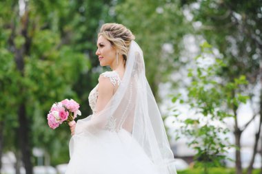 Güzel sarışın gelin bahar bahçesinde poz veriyor.