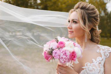 Güzel sarışın gelin bahar bahçesinde poz veriyor.