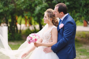 Güzel yeni evliler bahar parkında poz veriyorlar.