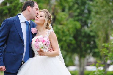 Güzel yeni evliler bahar parkında poz veriyorlar.