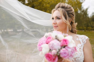 Güzel sarışın gelin bahar bahçesinde poz veriyor.