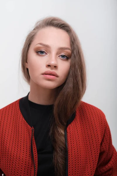 Teenager girl with fluffy hair wearing red jacket posing in studio