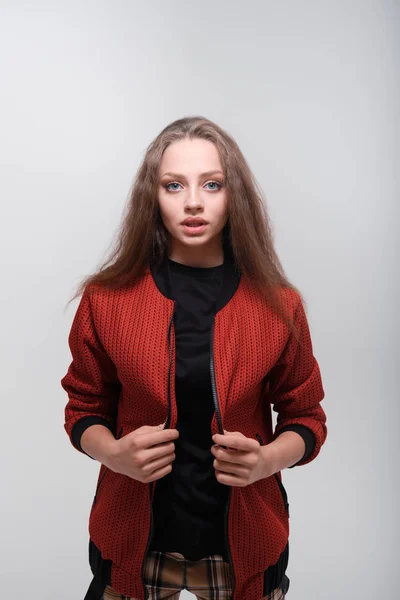 Teenager girl with fluffy hair wearing red jacket posing in studio