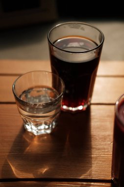 Tahta masanın üzerinde su olan bir bardak viski.