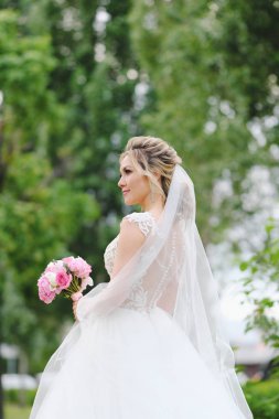 Güzel sarışın gelin bahar bahçesinde poz veriyor.