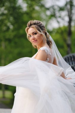 Güzel sarışın gelin bahar bahçesinde poz veriyor.