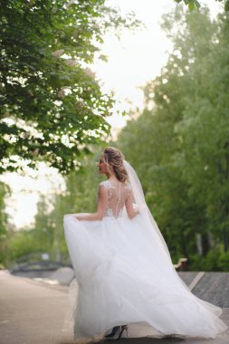 Güzel sarışın gelin bahar bahçesinde poz veriyor.