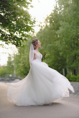 Güzel sarışın gelin bahar bahçesinde poz veriyor.