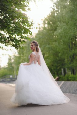 Güzel sarışın gelin bahar bahçesinde poz veriyor.