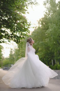 Güzel sarışın gelin bahar bahçesinde poz veriyor.