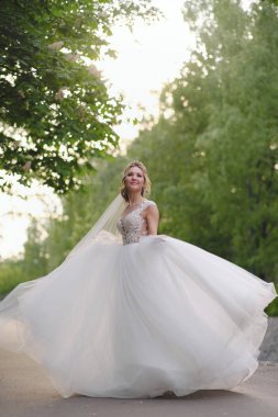 Güzel sarışın gelin bahar bahçesinde poz veriyor.