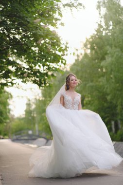 Güzel sarışın gelin bahar bahçesinde poz veriyor.