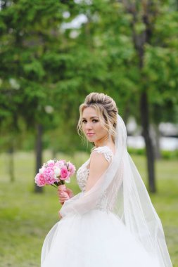 Güzel sarışın gelin bahar bahçesinde poz veriyor.
