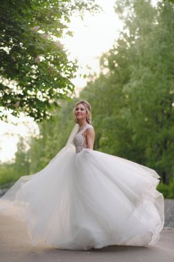 Güzel sarışın gelin bahar bahçesinde poz veriyor.