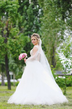 Güzel sarışın gelin bahar bahçesinde poz veriyor.