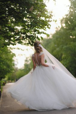 Güzel sarışın gelin bahar bahçesinde poz veriyor.