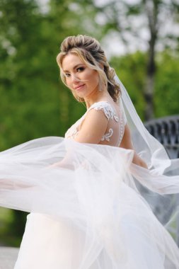 Güzel sarışın gelin bahar bahçesinde poz veriyor.