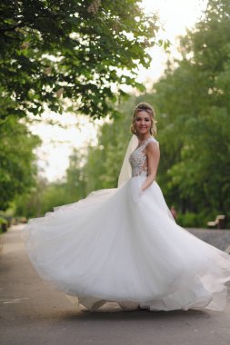 Güzel sarışın gelin bahar bahçesinde poz veriyor.