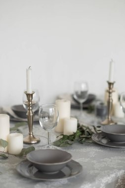Dining table served for guests with festive candles and grey utensil