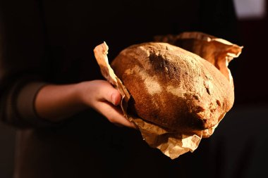 Elinde bir somun taze ekmek tutan kişi