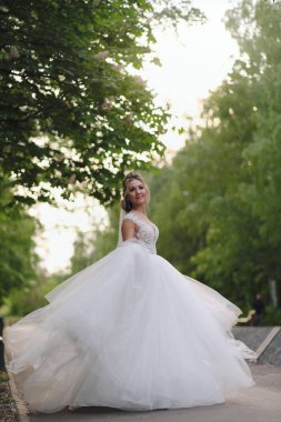 Güzel sarışın gelin bahar bahçesinde poz veriyor.