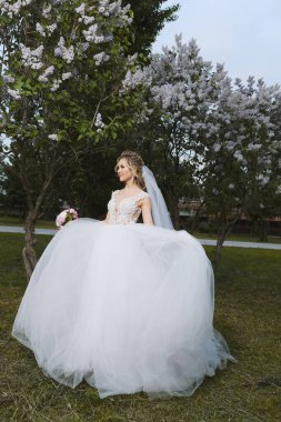 Güzel sarışın gelin bahar bahçesinde poz veriyor.