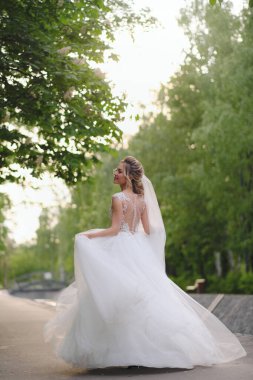 Güzel sarışın gelin bahar bahçesinde poz veriyor.