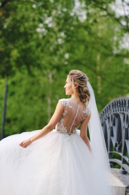 Güzel sarışın gelin bahar bahçesinde poz veriyor.