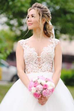 Güzel sarışın gelin bahar bahçesinde poz veriyor.