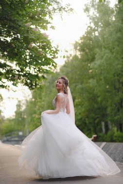 Güzel sarışın gelin bahar bahçesinde poz veriyor.