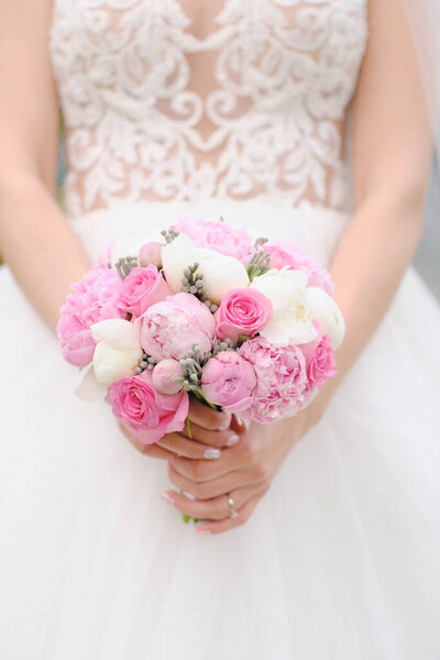 Close view of bride in white dress holding wedding bouquet  