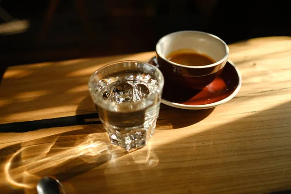 Svart Kaffe Kopp Och Ett Genomskinligt Glas Med Vatten Träbakgrund — Stockfoto
