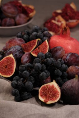 Mor İtalyan incir, üzüm ve gri arka plan üzerine nar sepet tabak.