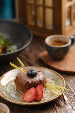 Çilekli çikolatalı tatlı ve arka planda bir fincan kahve. fotoğraf kafede..