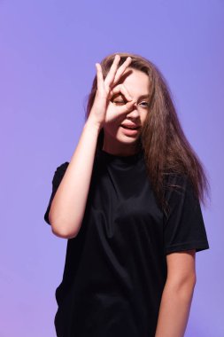 Tamam jest yapan genç bir kadının stüdyo fotoğrafı. 