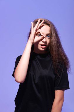 Tamam jest yapan genç bir kadının stüdyo fotoğrafı. 