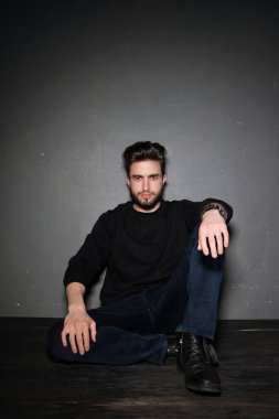 yakışıklı genç sakallı adam yerde oturuyor.  