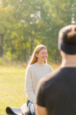 Kadın yoga yapıyor ve parkta lotus pozisyonunda meditasyon yapıyor.