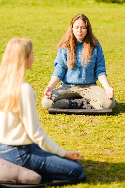 Un grupo de jóvenes meditan al aire libre en un parque . — Foto de Stock