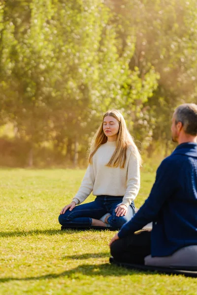 Un grupo de jóvenes meditan al aire libre en un parque . — Foto de Stock