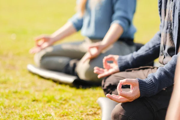 Jóvenes deportistas practicando yoga, haciendo ejercicio Padmasana, pose de Loto, con gesto mudra, ejercitándose . — Foto de Stock