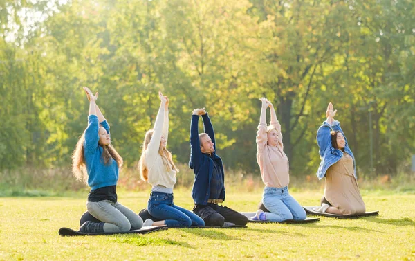 Un grupo de jóvenes meditan al aire libre en un parque . — Foto de Stock