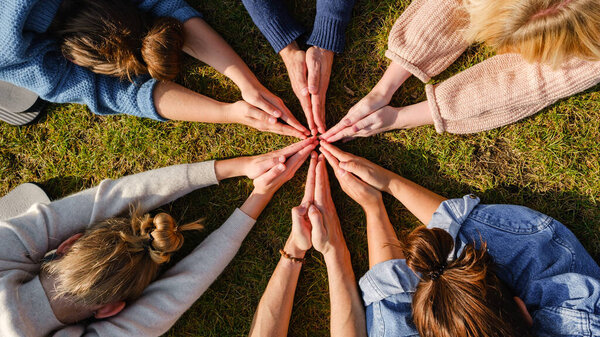 Close up of hands of people sitting outdoors on green grass after doing yoga