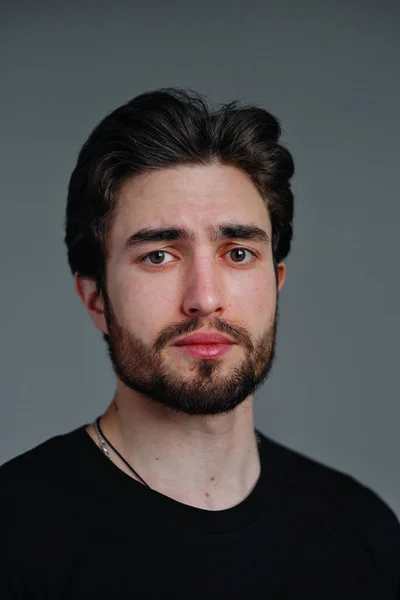 Retrato de close-up de um jovem homem elegante com barba e cabelo escuro em uma camiseta preta — Fotografia de Stock