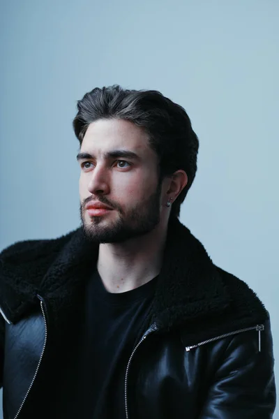 Um grande retrato de um jovem elegante com barba e cabelo escuro em uma jaqueta de couro preto — Fotografia de Stock