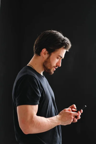 Närbild porträtt av en ung snygg man med skägg och mörkt hår i en svart T-shirt. — Stockfoto