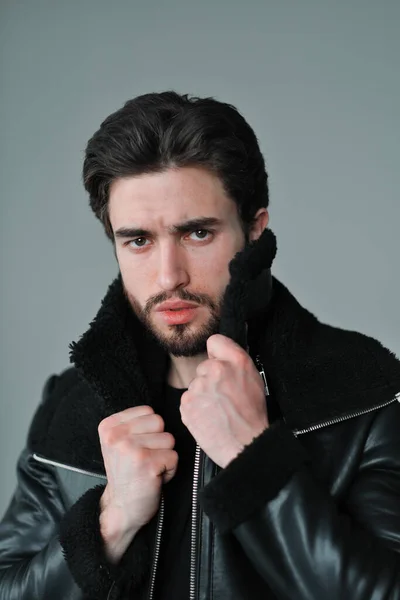 Ett stort porträtt av en stilig ung man med skägg och mörkt hår i svart skinnjacka — Stockfoto