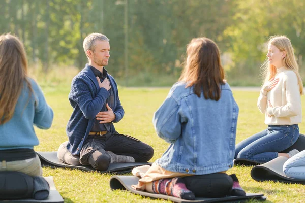 Een groep jongeren mediteert buiten in een park. — Stockfoto